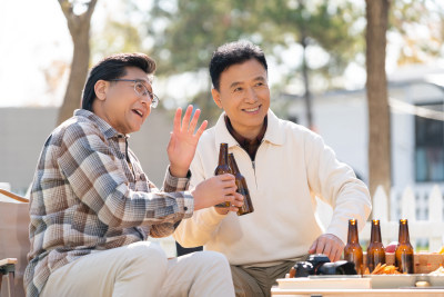 两个老年男人坐在露营地喝啤酒