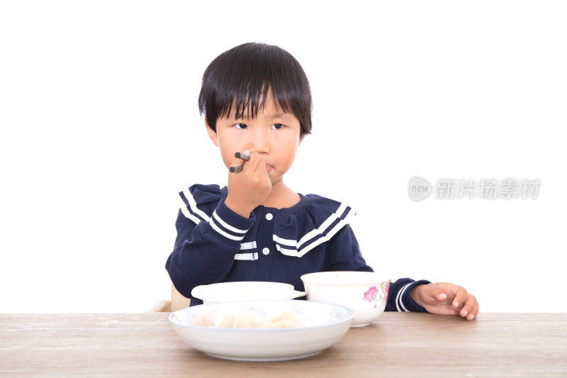 中国三岁小女孩在白背景前的餐桌上吃饭