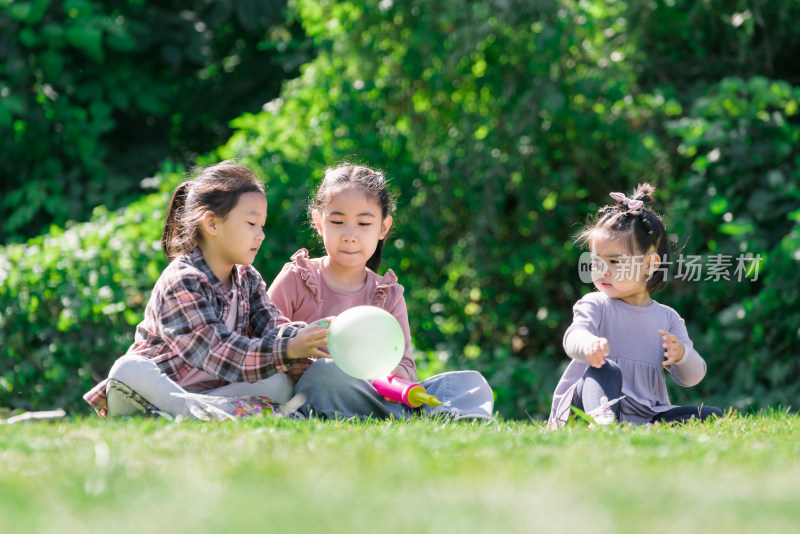 秋天午后三个坐在草坪上玩气球的女孩