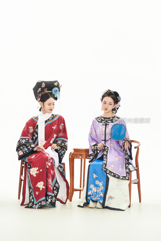 白色背景下穿着中国清朝服饰的两名少女