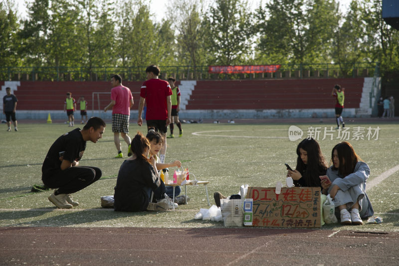 足球场边年轻人摆摊售卖DIY娃娃