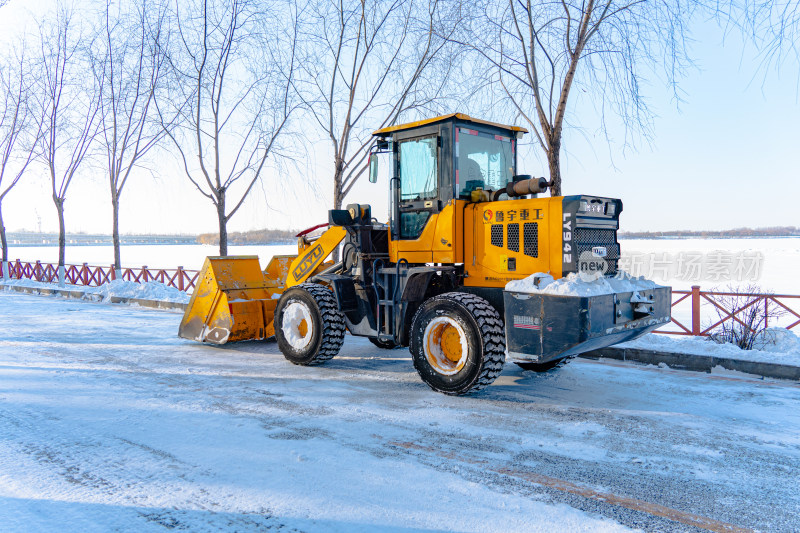 黄色装载机在积雪道路上作业