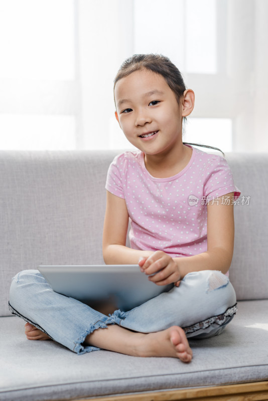 中国女孩坐在沙发上使用平板电脑