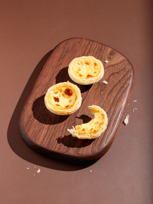 木质砧板上摆放着的早餐美食蛋挞