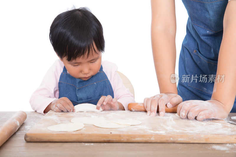 小姑娘在妈妈身旁认真的学习包饺子