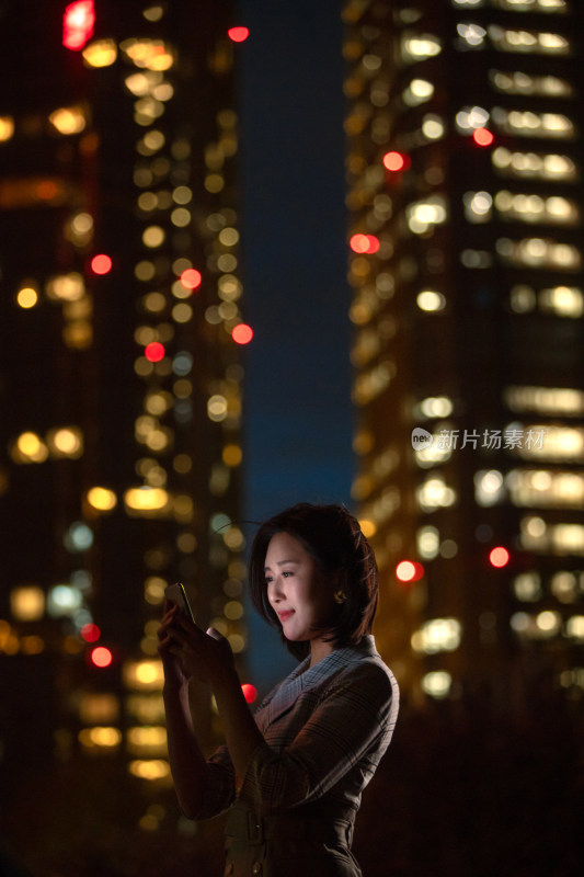 晚上在户外看手机的商务女白领