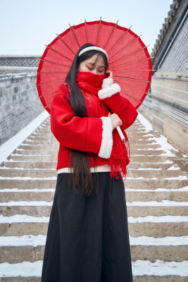 雪后在老城古巷穿着喜庆服饰的亚洲少女