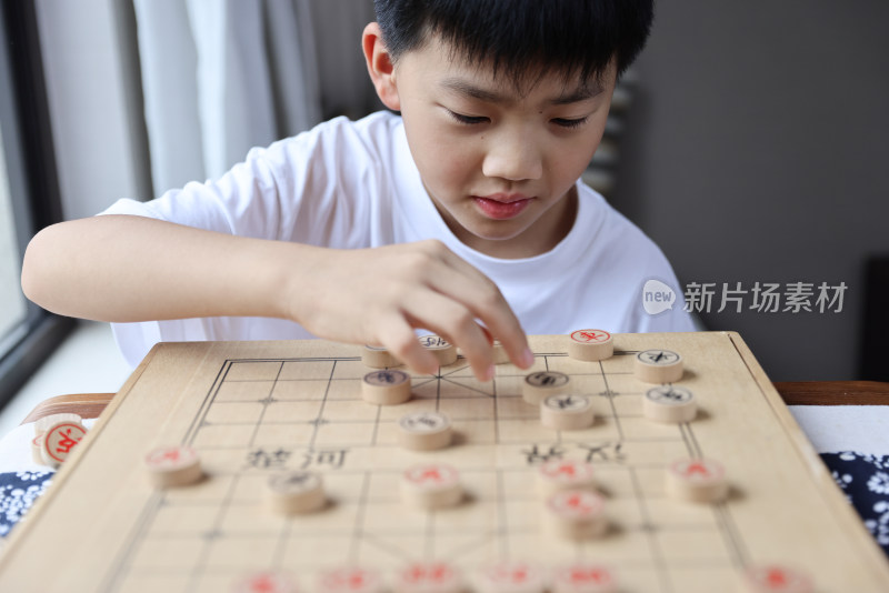 可爱的男孩在窗边下中国象棋