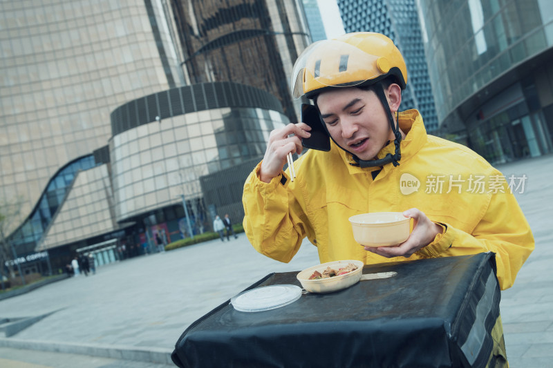 边吃饭边打电话的青年外卖员