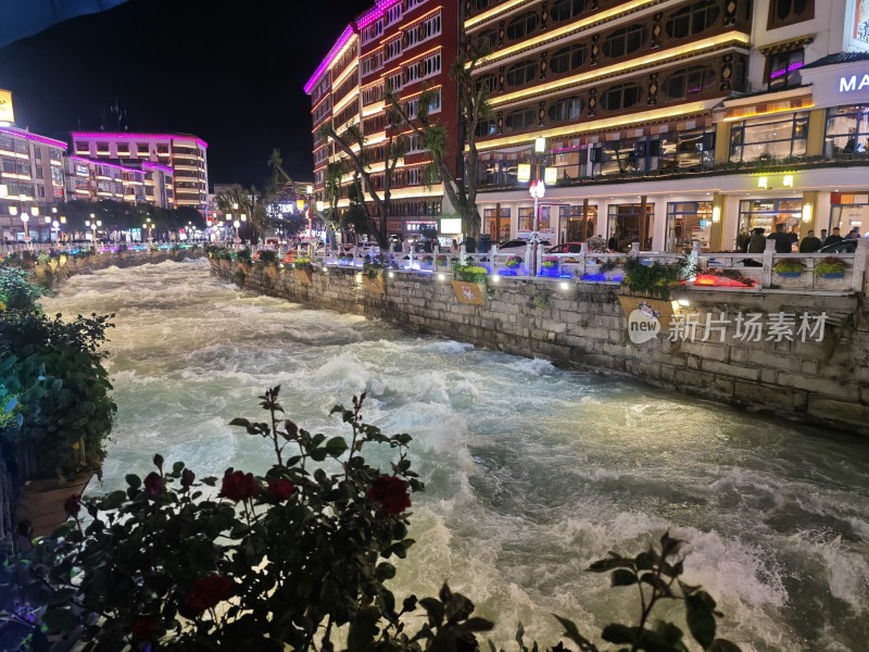 夜晚湍急水流旁的城市街道景象