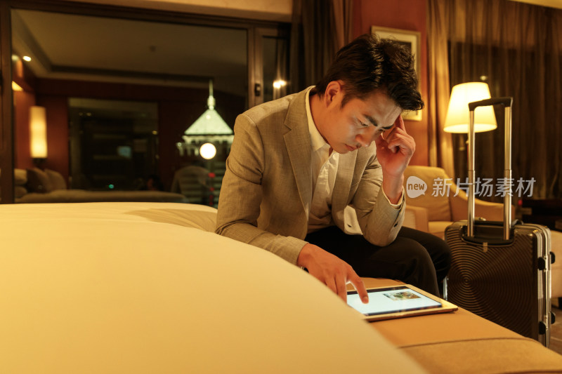 青年男人坐在酒店客房里用平板电脑