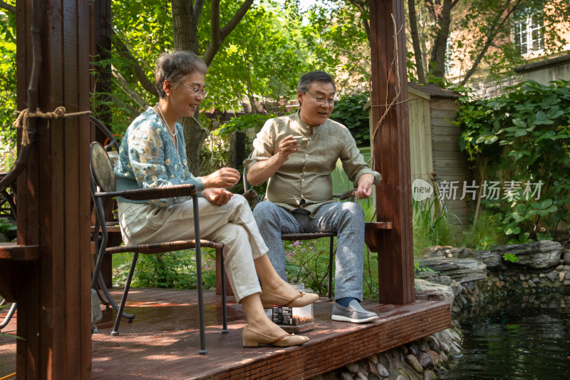 老年夫妇在院子里喝茶喂鱼