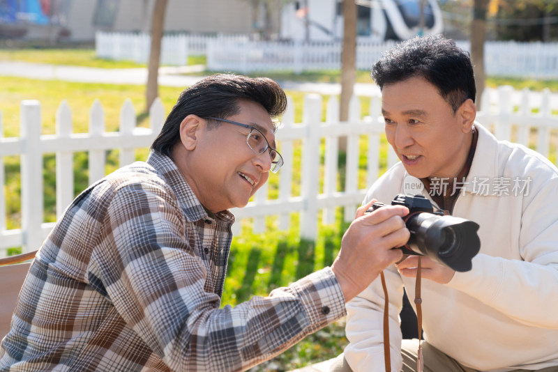 两个老年男人坐在露营地看数码相机