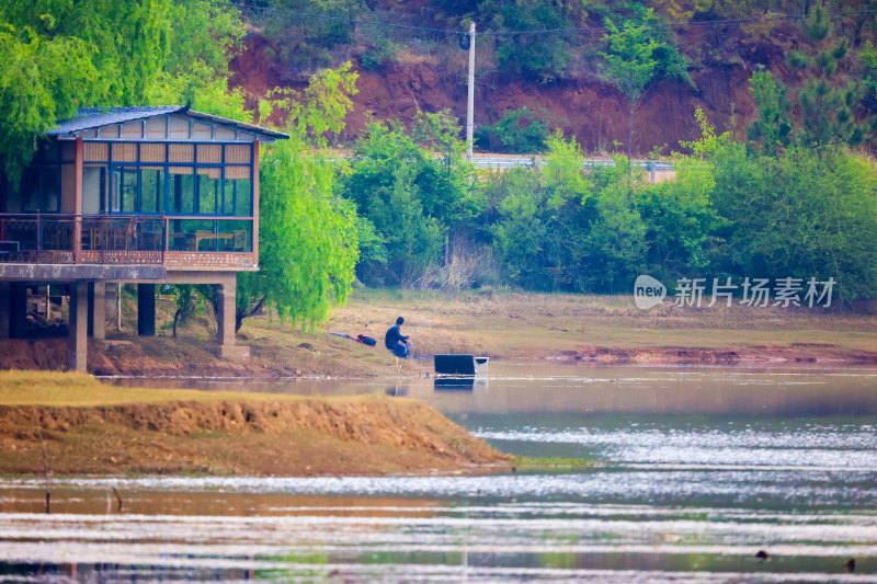 湖边小屋旁的人垂钓场景