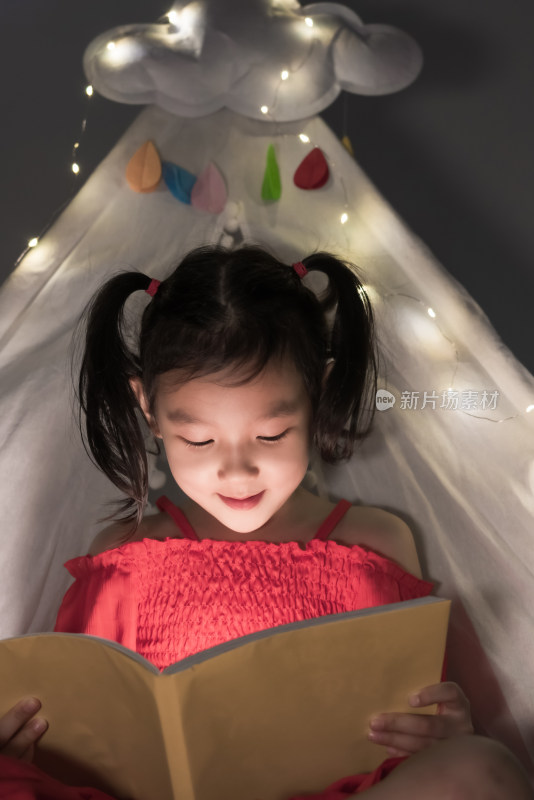 夜晚在白色帐篷里读书的女孩