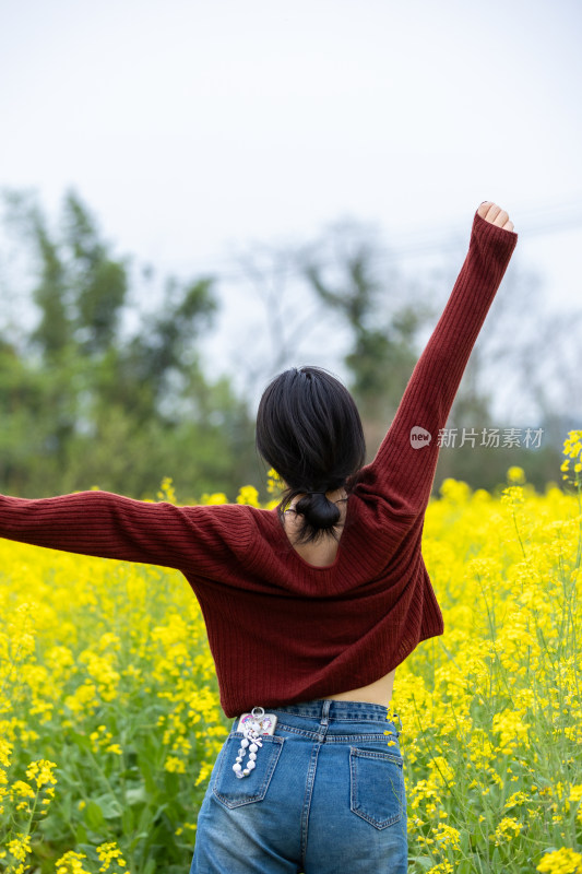 轻松休闲美女在油菜花从前张开双臂伸懒腰