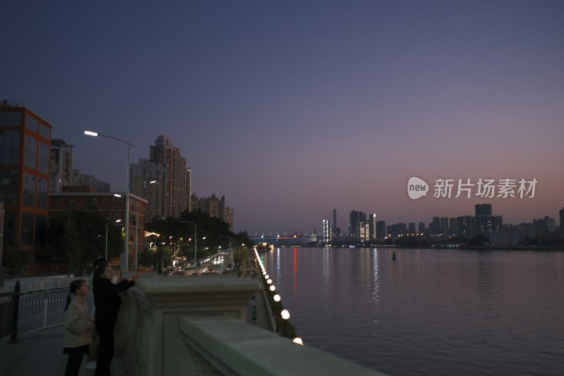 江边城市夜景，有人在观景台拍照