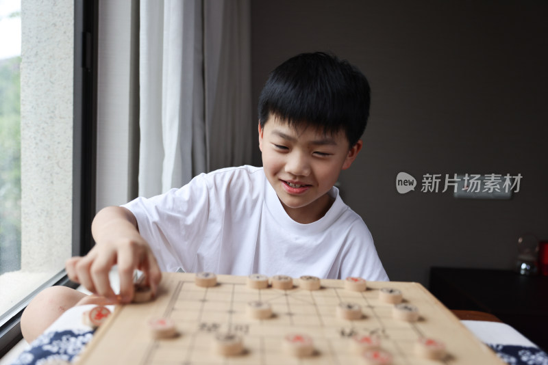 可爱的男孩在窗边下中国象棋