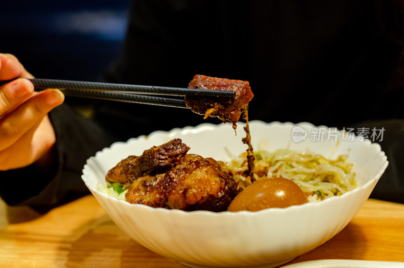 从卤肉饭中碗里夹起一块肉