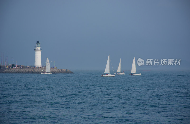 山东青岛大海上的灯塔和航行的帆船