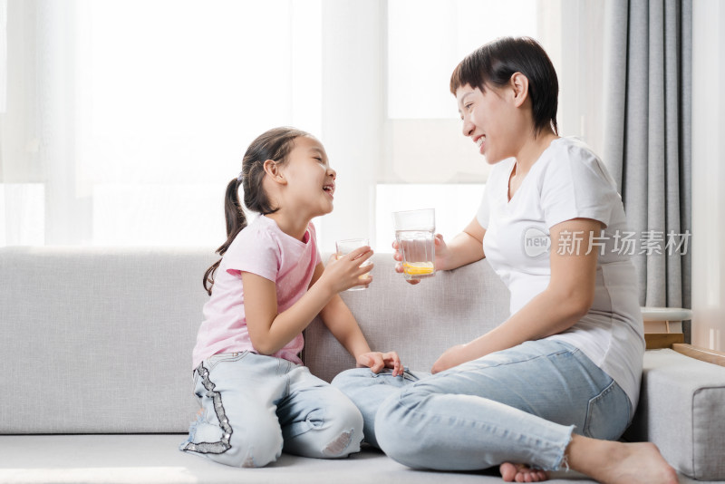 坐在沙发上喝水休息的中国母女