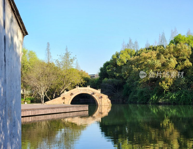 河畔拱形石桥与绿树风景