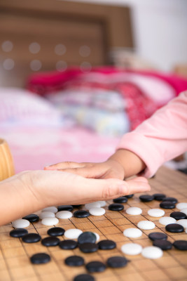 围棋棋盘前成年人的手和孩子的手