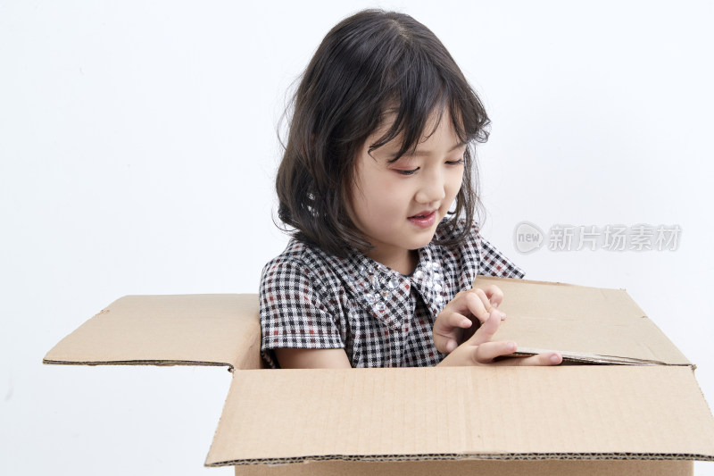 躲在纸箱中玩耍的调皮可爱亚洲小女孩（儿童）