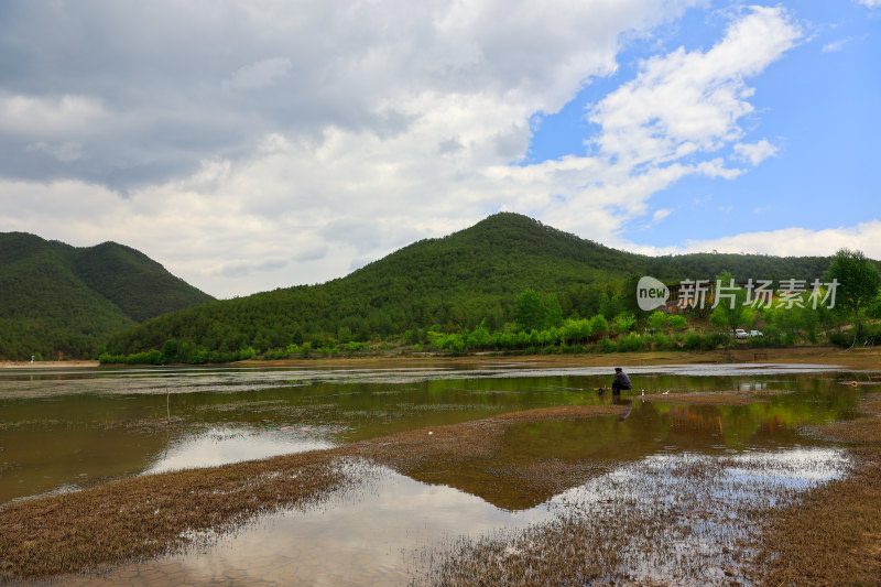 湖边小屋旁的人垂钓场景