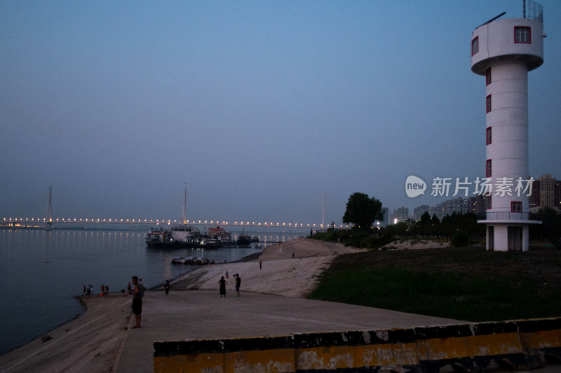 江边瞭望塔下的人们与江上船只夜景