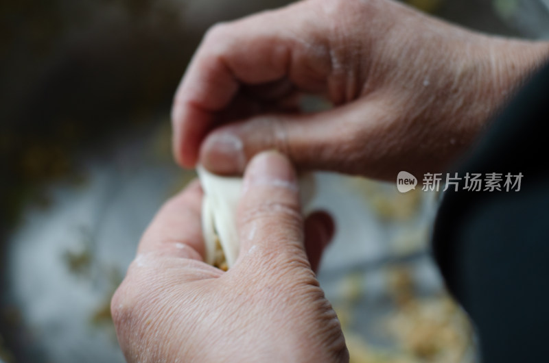 正在包饺子的母亲的手部特写