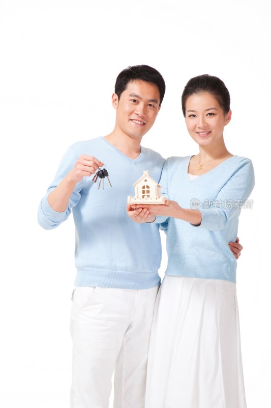 幸福的夫妻拿着钥匙和房子模型
