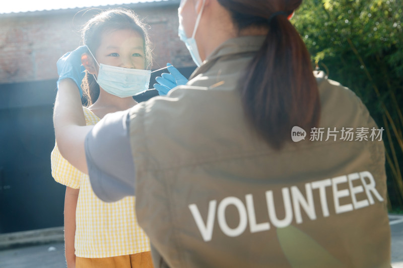 社区志愿者帮小女孩戴口罩