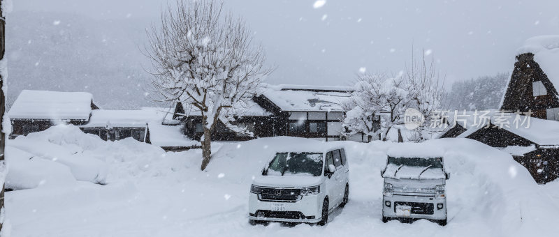 雪中村落景象，两辆汽车停在积雪中