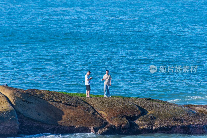 东山岛海边岩石上站立的两个人