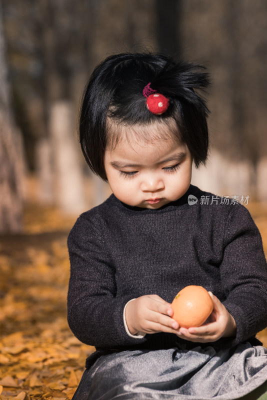 深秋坐在公园落满黄叶的草地上的女孩特写