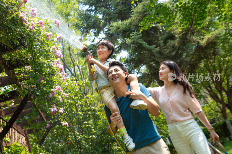 幸福的一家三口在院子里浇水