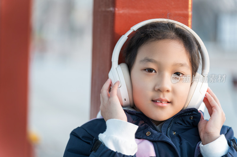 冬日暖阳坐在公园长廊带耳机欣赏音乐的女孩