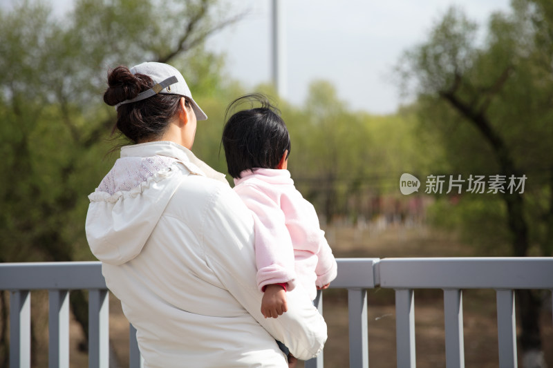 站在桥头抱着孩子的年轻妈妈