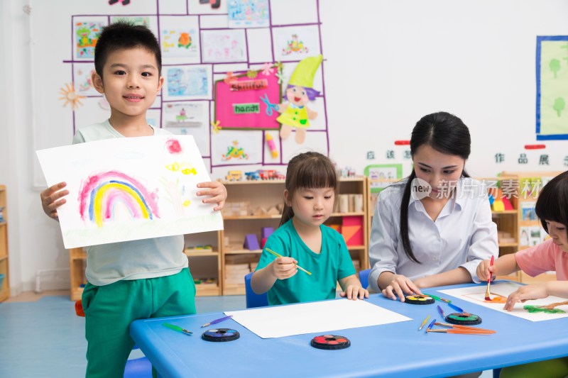 幼儿园女老师和儿童展示绘画作品