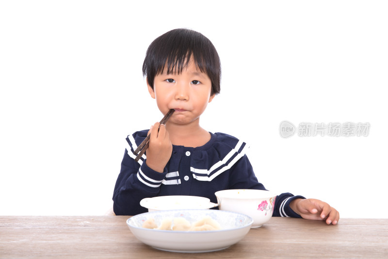 中国三岁小女孩在白背景前的餐桌上吃饭