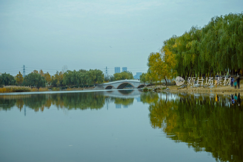 湖面倒映石桥树木的自然风光全景