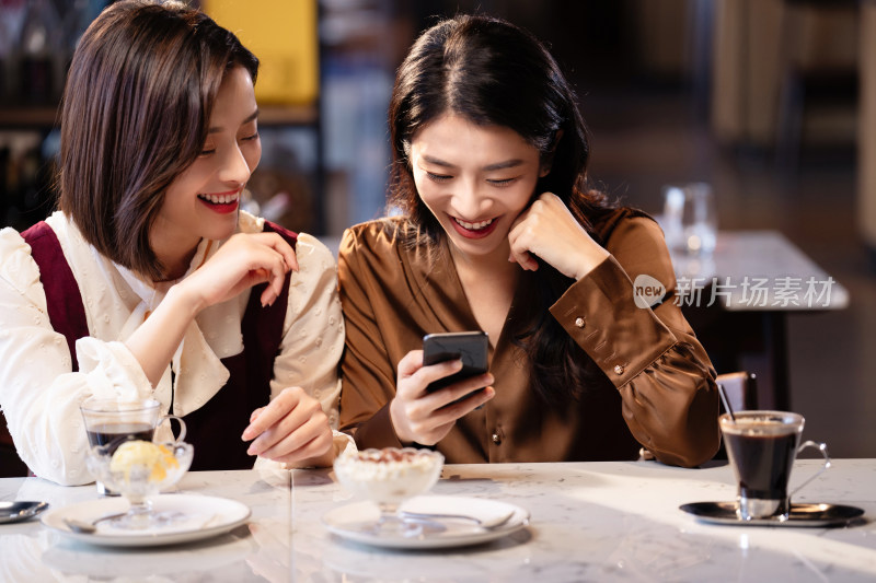 年轻闺蜜在咖啡馆使用手机