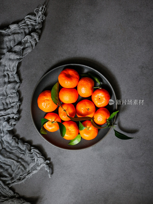 黑色桌面上，一盘子的广西新鲜水果砂糖桔