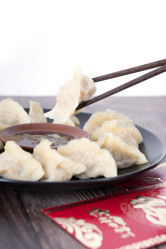 筷子夹起盘子里的饺子和盘子下的节日红包