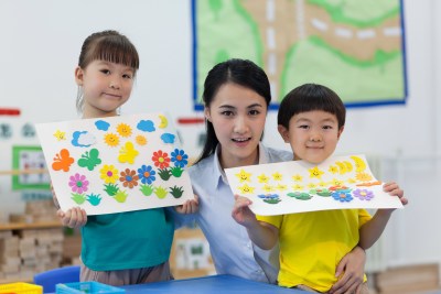 幼儿园女老师辅导儿童做手工