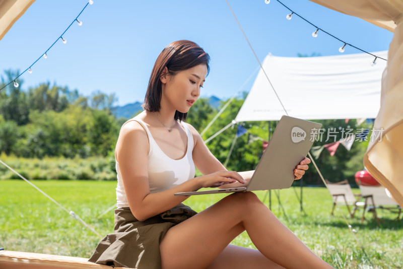 女孩坐帐篷里使用电脑