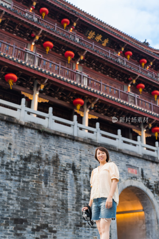 身穿休闲装女子站在古建筑前拍照