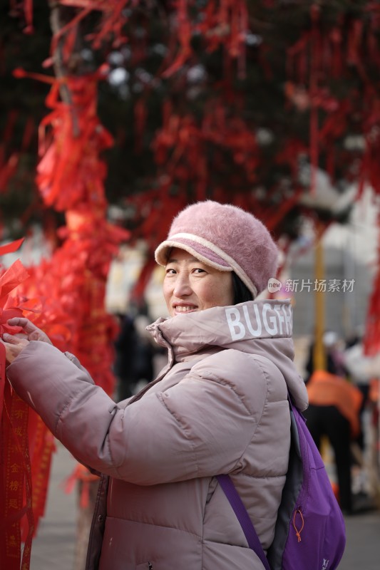 身穿冬装的女士在挂红色祈福带