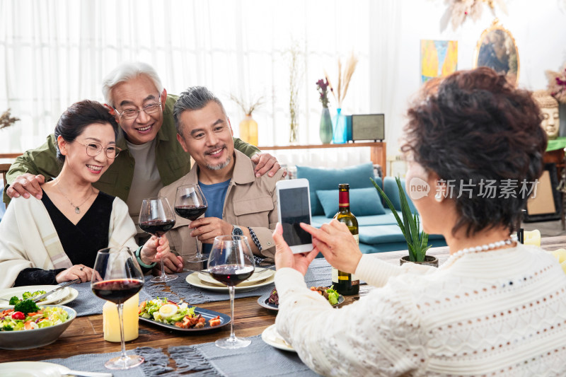 聚餐时快乐的中老年人用手机拍照